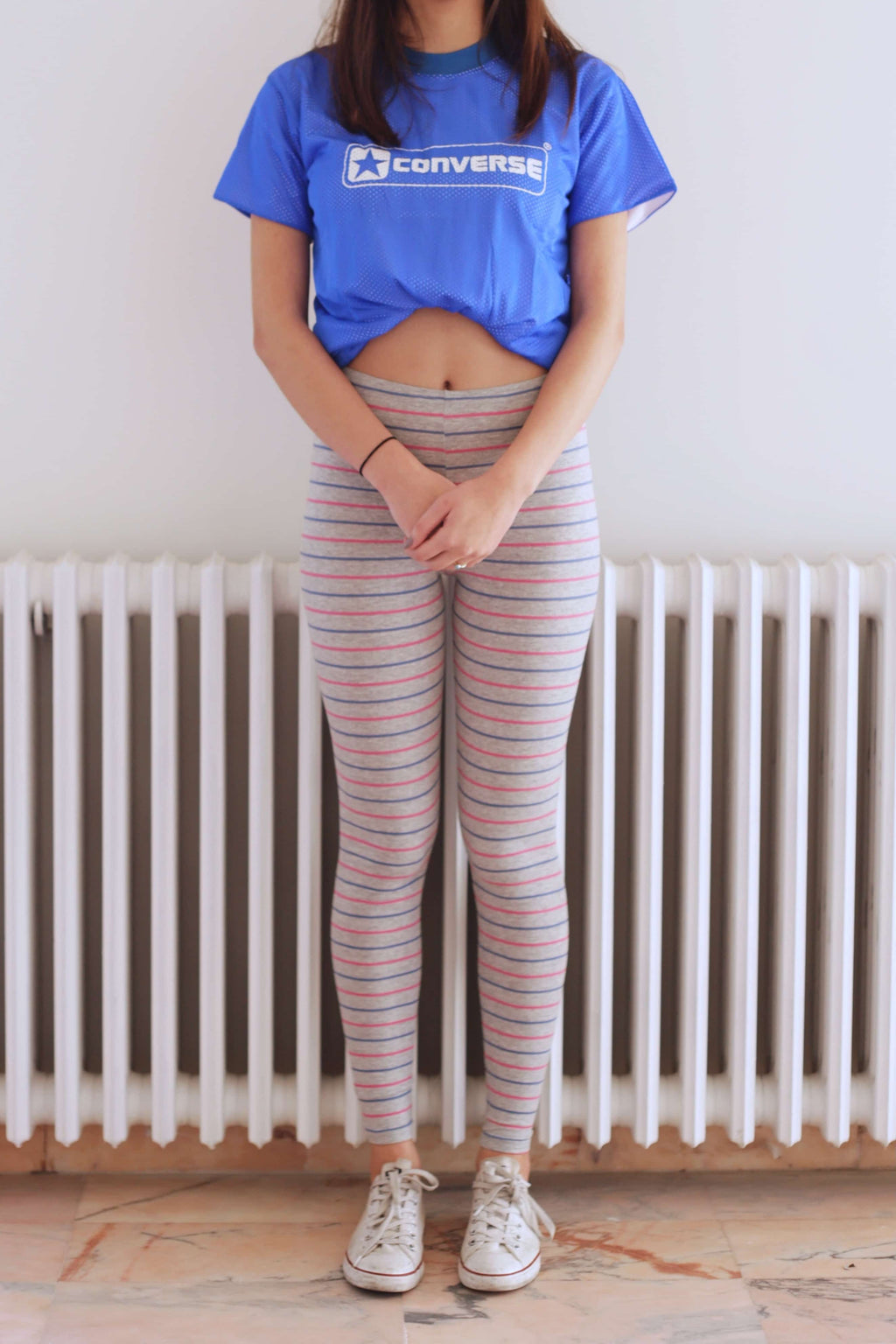 Solar vintage 80s micro stripe cotton leggings worn on a female model — fine pink and blue stripes on heather grey base, slim full-length cut, styled with white Converse sneakers and blue Converse t-shirt, front view