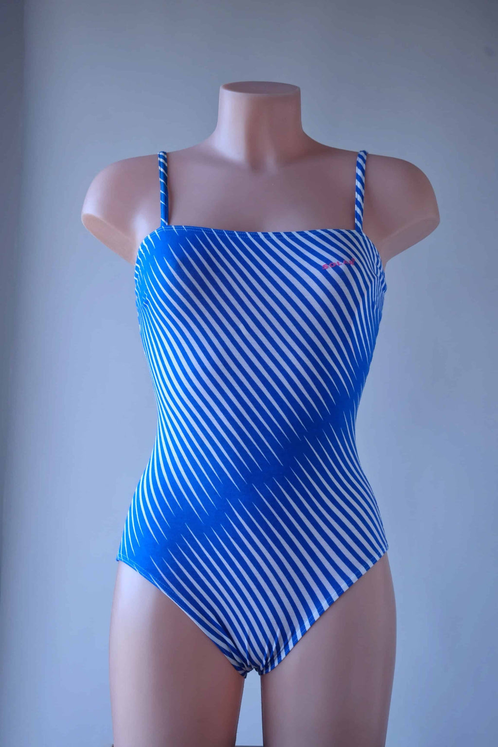 Solar vintage 80s diagonal stripe spaghetti strap leotard worn on a mannequin — blue and white diagonal cross stripes, straight bandeau neckline, spaghetti straps, high cut leg, front view