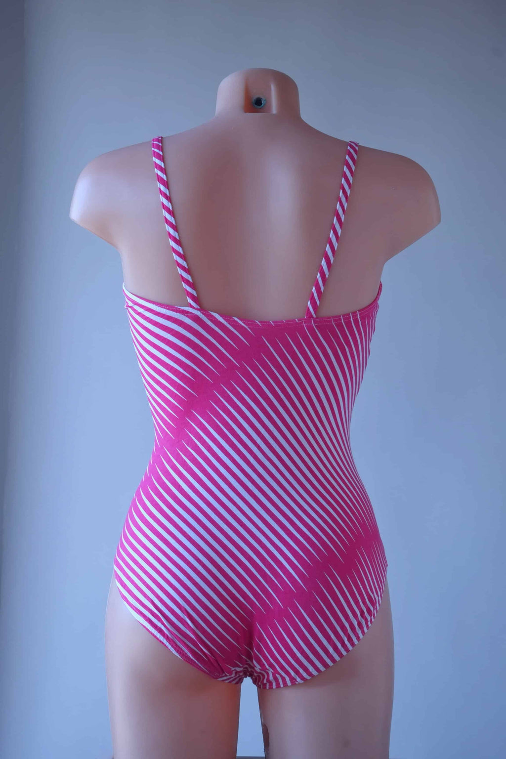 Solar vintage 80s diagonal stripe spaghetti strap leotard worn on a mannequin — fuchsia and white diagonal cross stripes, straight bandeau neckline, spaghetti straps, high cut leg, back view