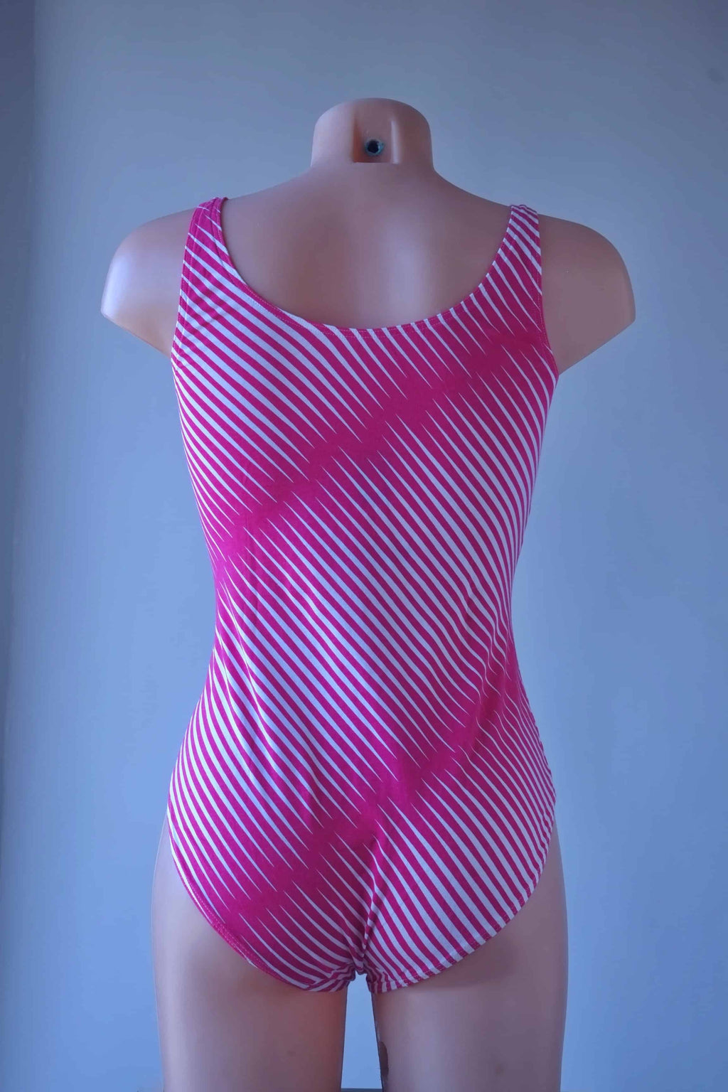 Rear view of a mannequin wearing a pink and white diagonal striped Solar leotard with tank-style straps and a high-cut leg.