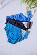 Three pairs of SOLAR brand vintage 80s men's swim briefs in shades of blue with white diagonal side panels, displayed flat on a white background.