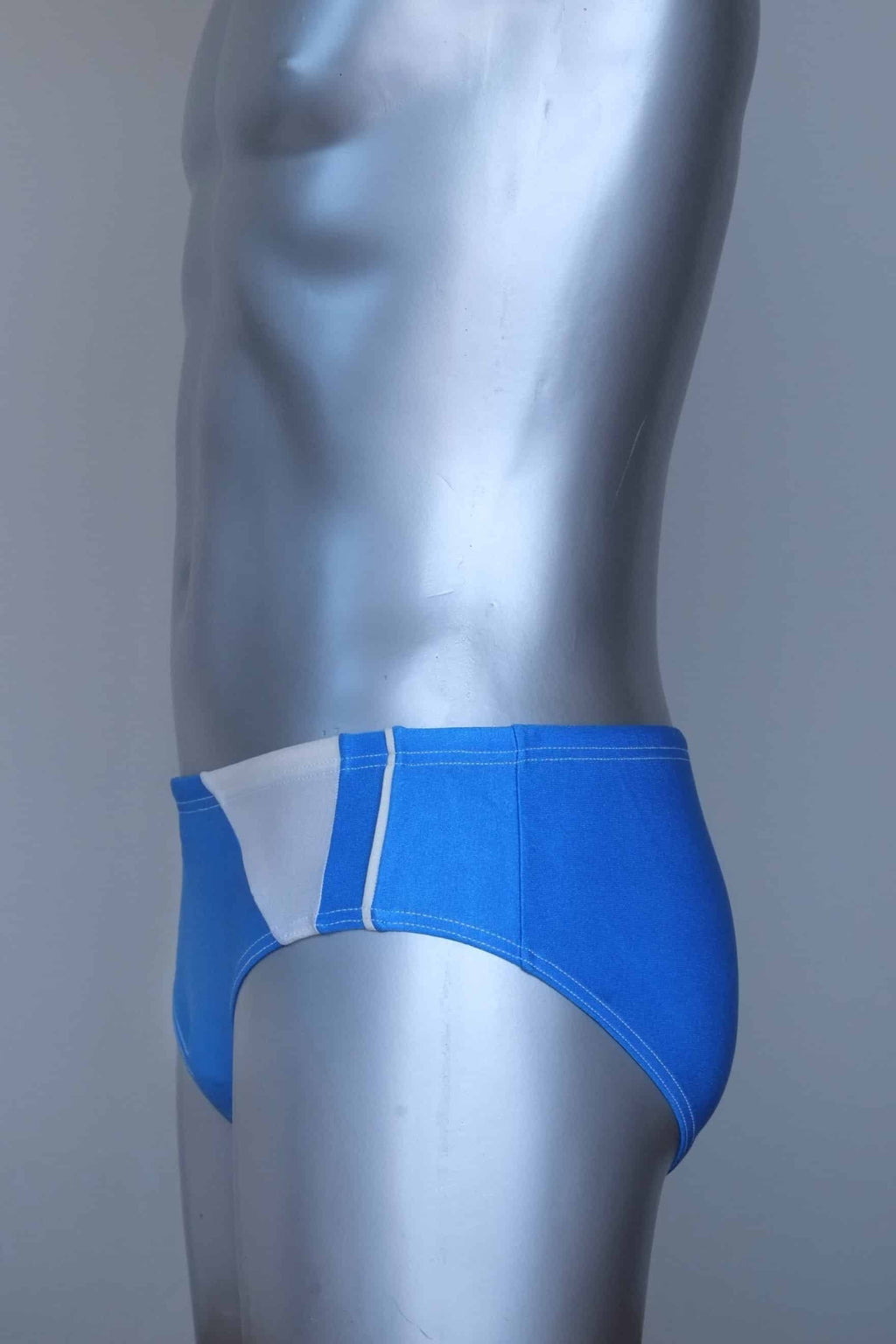 Side view of a vintage Blue men's swim briefs on a silver mannequin against a gray background