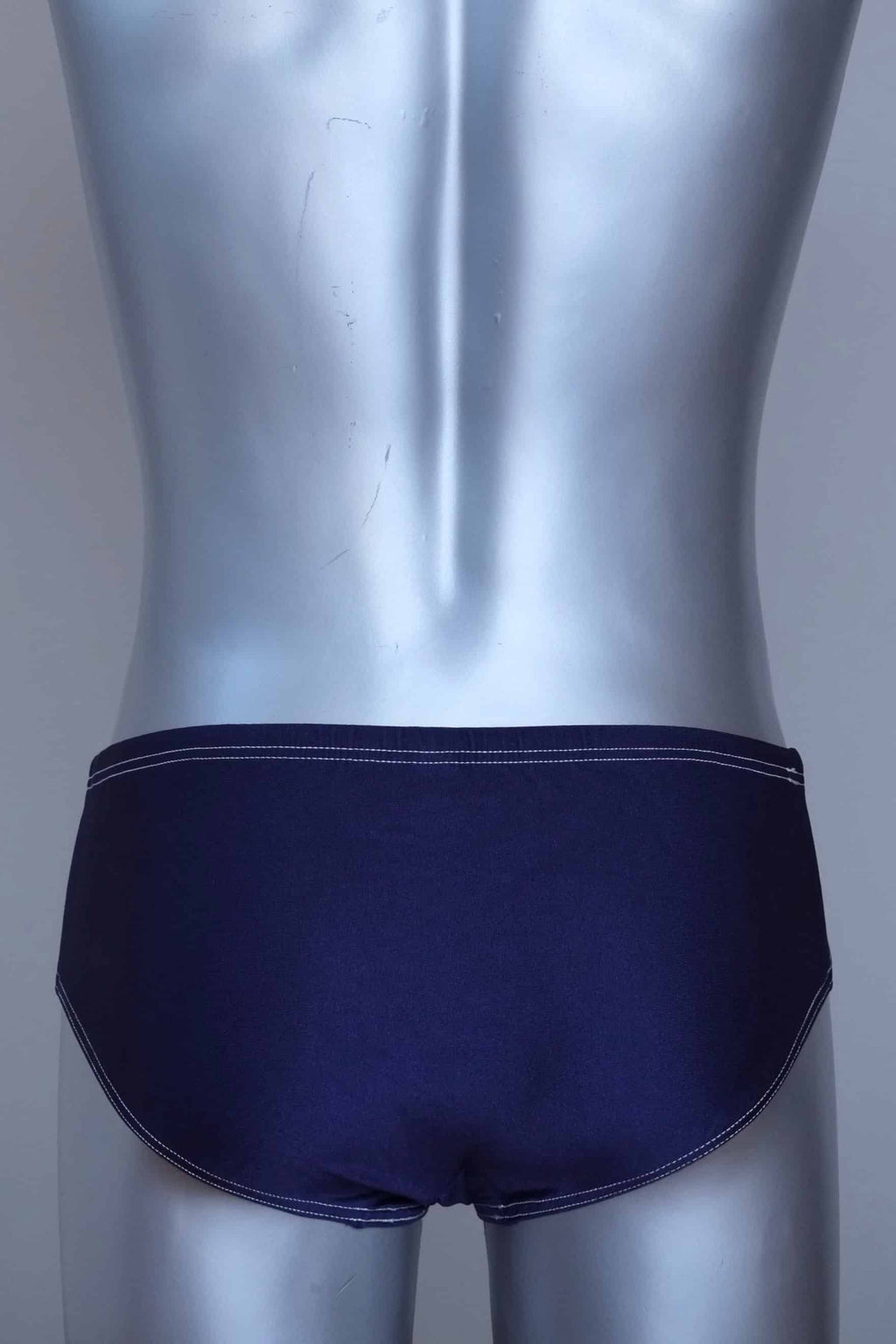 Back view of a vintage navy men's swim briefs on a silver mannequin against a gray background