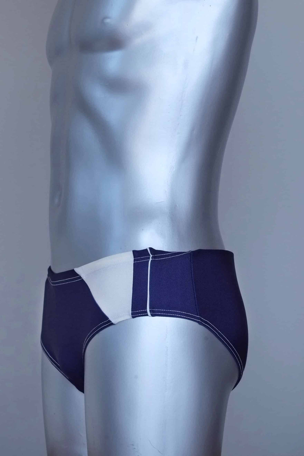 Side view of a vintage navy men's swim briefs on a silver mannequin against a gray background