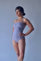 Solar vintage 80s pinstripe spaghetti strap leotard worn on a female model — heather grey with fine pink and blue pinstripes, straight bandeau neckline, spaghetti straps, high cut leg, three-quarter standing pose, front view