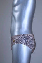 Side view of a Vintage SOLAR swim briefs with light brown snakeskin print pattern, gold metal logo badge, displayed on mannequin.