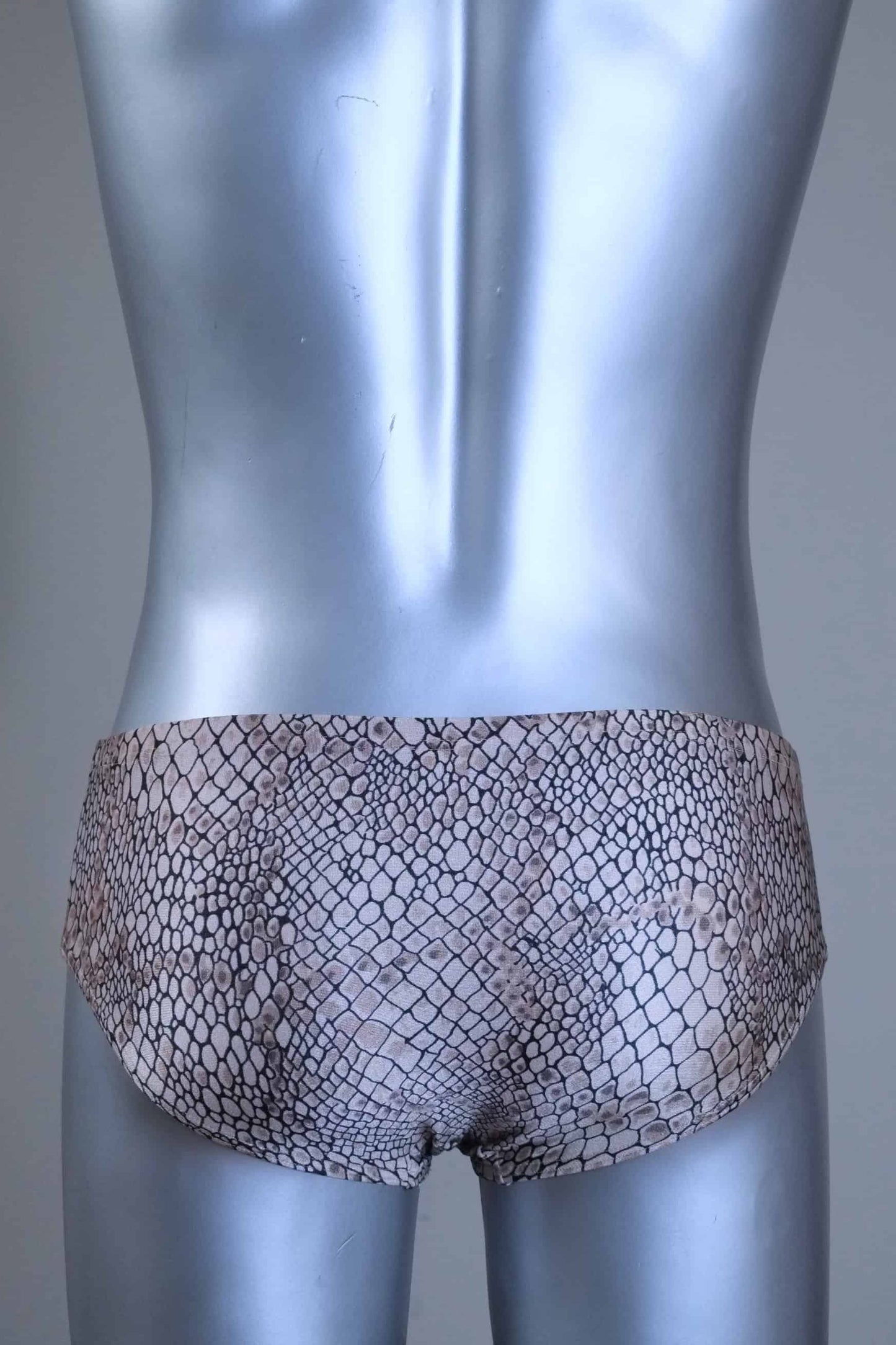 Back view of a Vintage SOLAR swim briefs with light brown snakeskin print pattern, gold metal logo badge, displayed on mannequin.