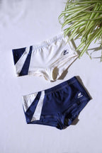 Two pairs of SOLAR brand vintage 80s men's square-cut swim briefs: one off-white with navy diagonal block, the other navy with white diagonal block, laid flat on a white background..