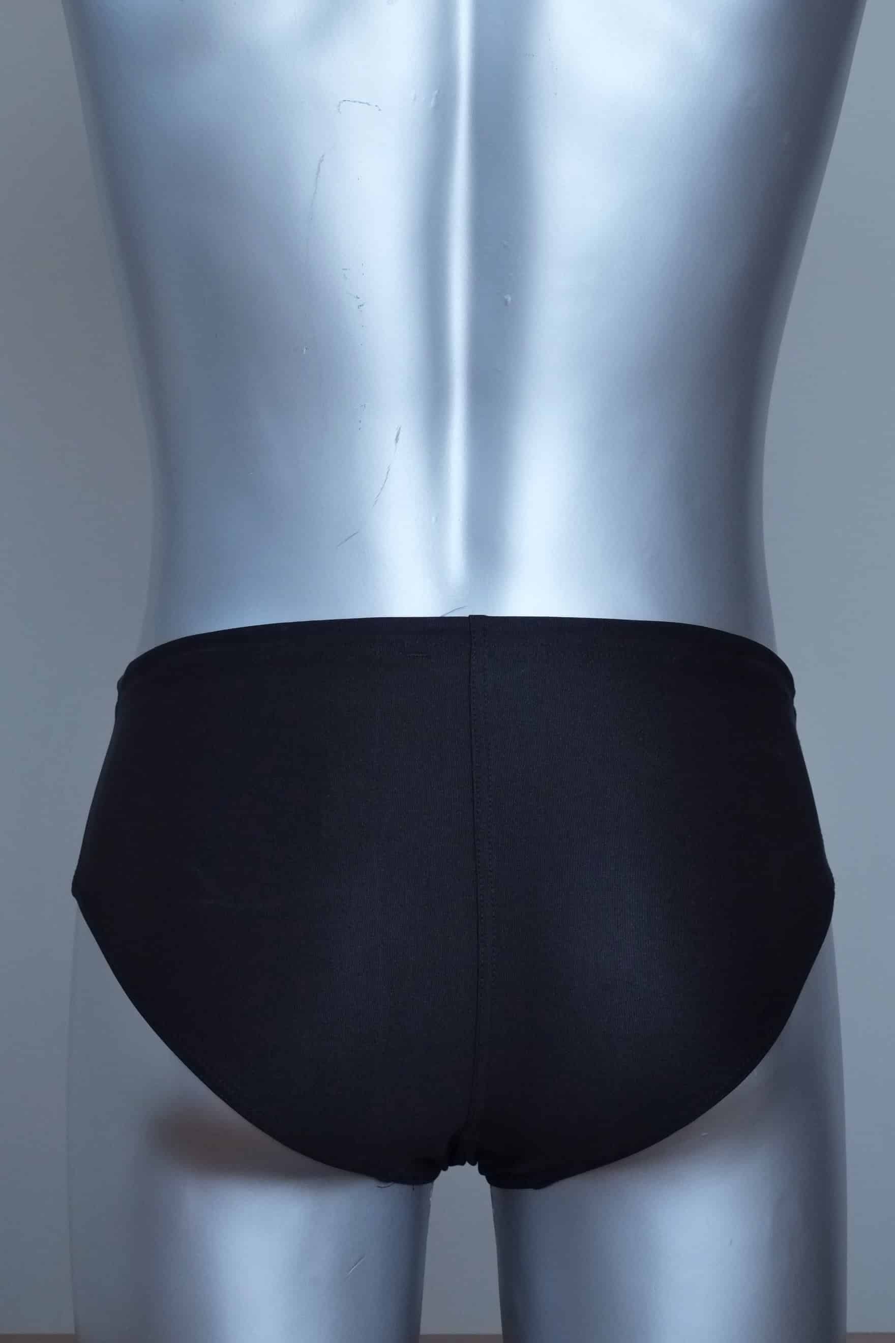 Back view of vintage black swim briefs with mannequin against a gray background