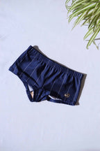 A single pair of SOLAR brand vintage 80s men's navy square-cut swim briefs with thin white vertical stripes and a gold metal logo on a white background.