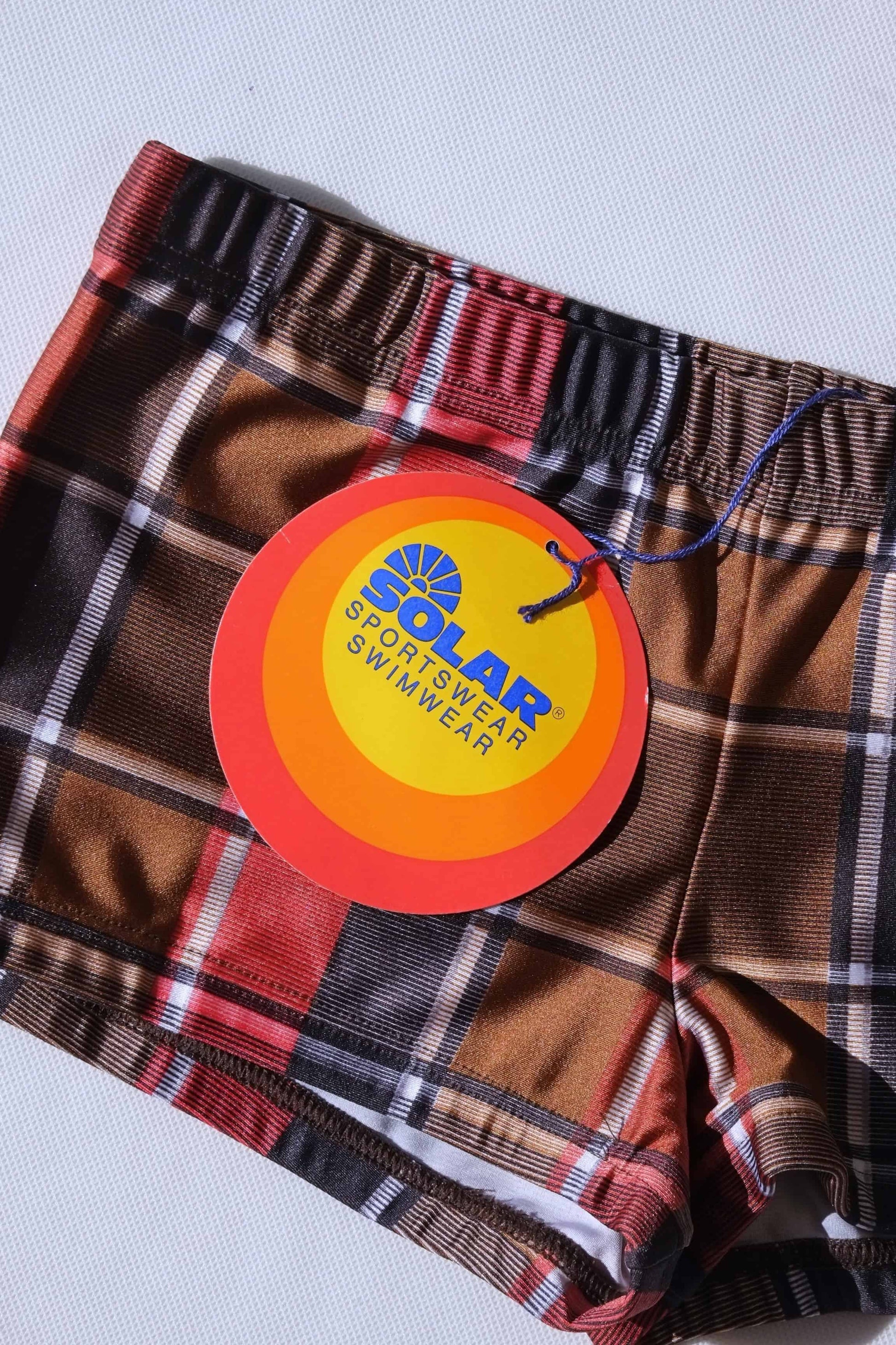 Vintage plaid swim briefs with a visible brand tag Solar sportswear on a light gray background