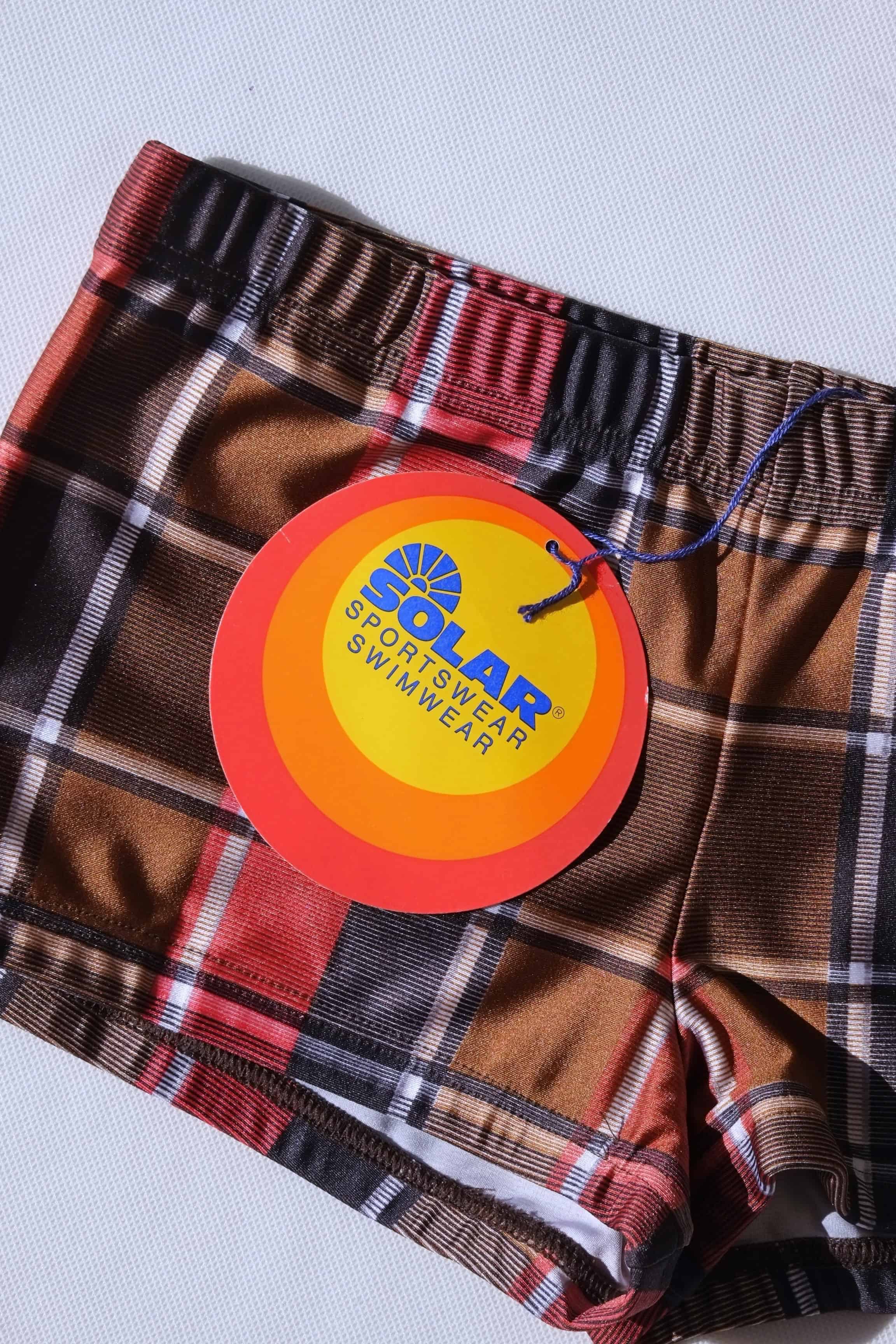 Vintage plaid swim briefs with a visible brand tag Solar sportswear on a light gray background