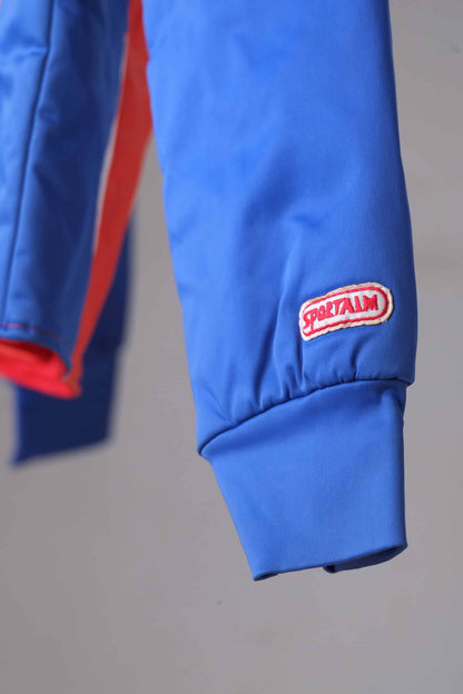 Detail shot of the sleeve of a vintage Sportalm ski jacket. The sleeve is blue and shows the word 'SPORTALM' in red and white.