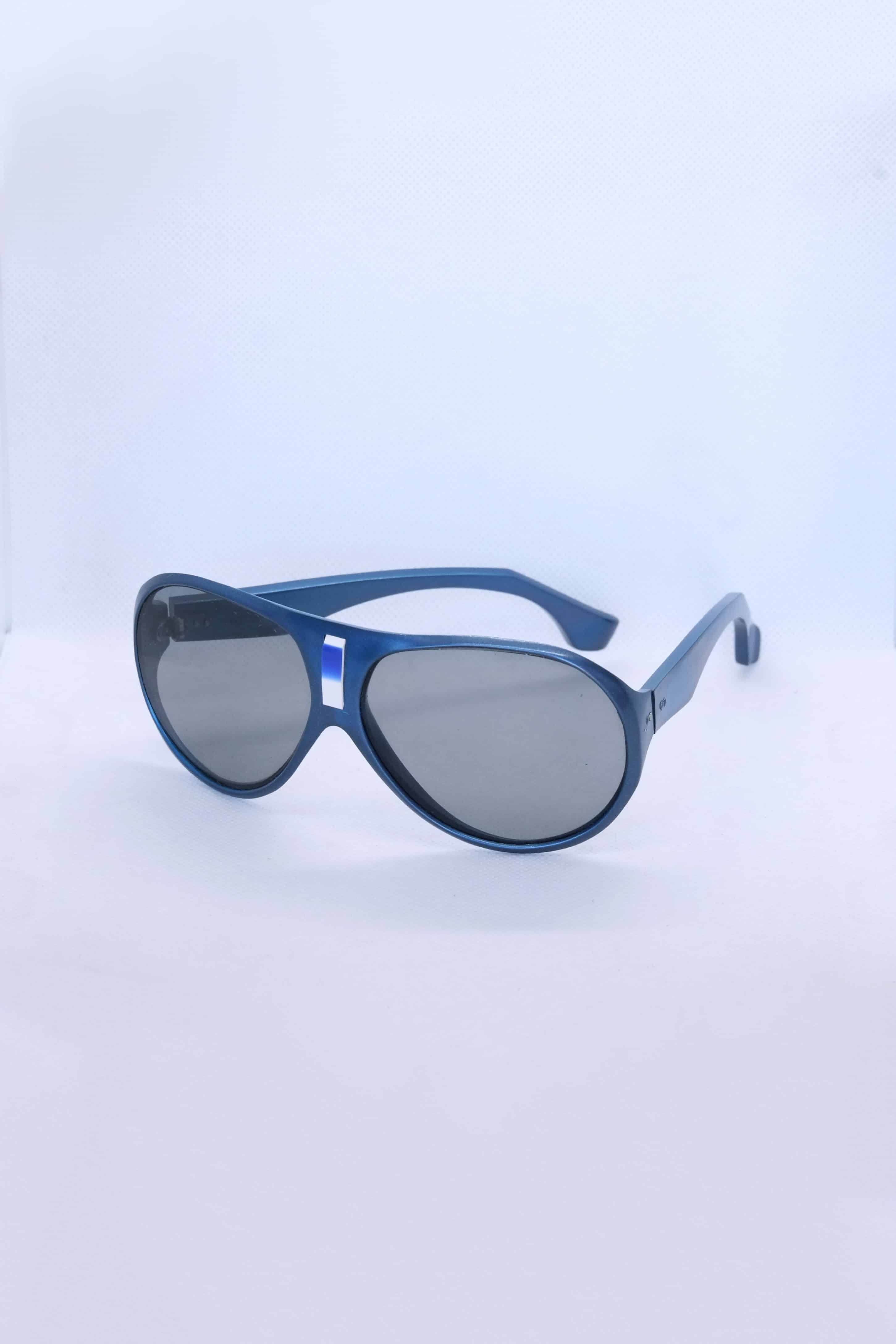 Angled view of vintage 1970s SKILOOK metallic blue shield-style alpine sunglasses with a silver metallic nose bridge accent and gray lenses against a white backdrop.