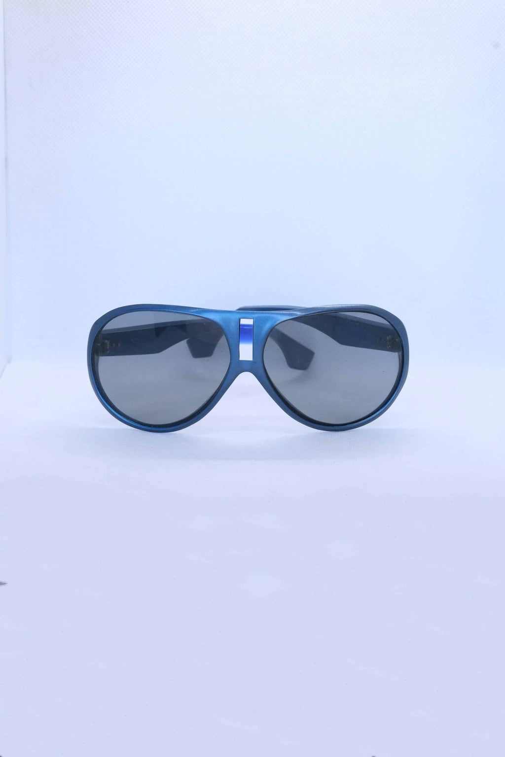 Front view of vintage 1970s SKILOOK metallic dark blue shield-style alpine sunglasses featuring a silver nose bridge insert and gray lenses against a white backdrop.