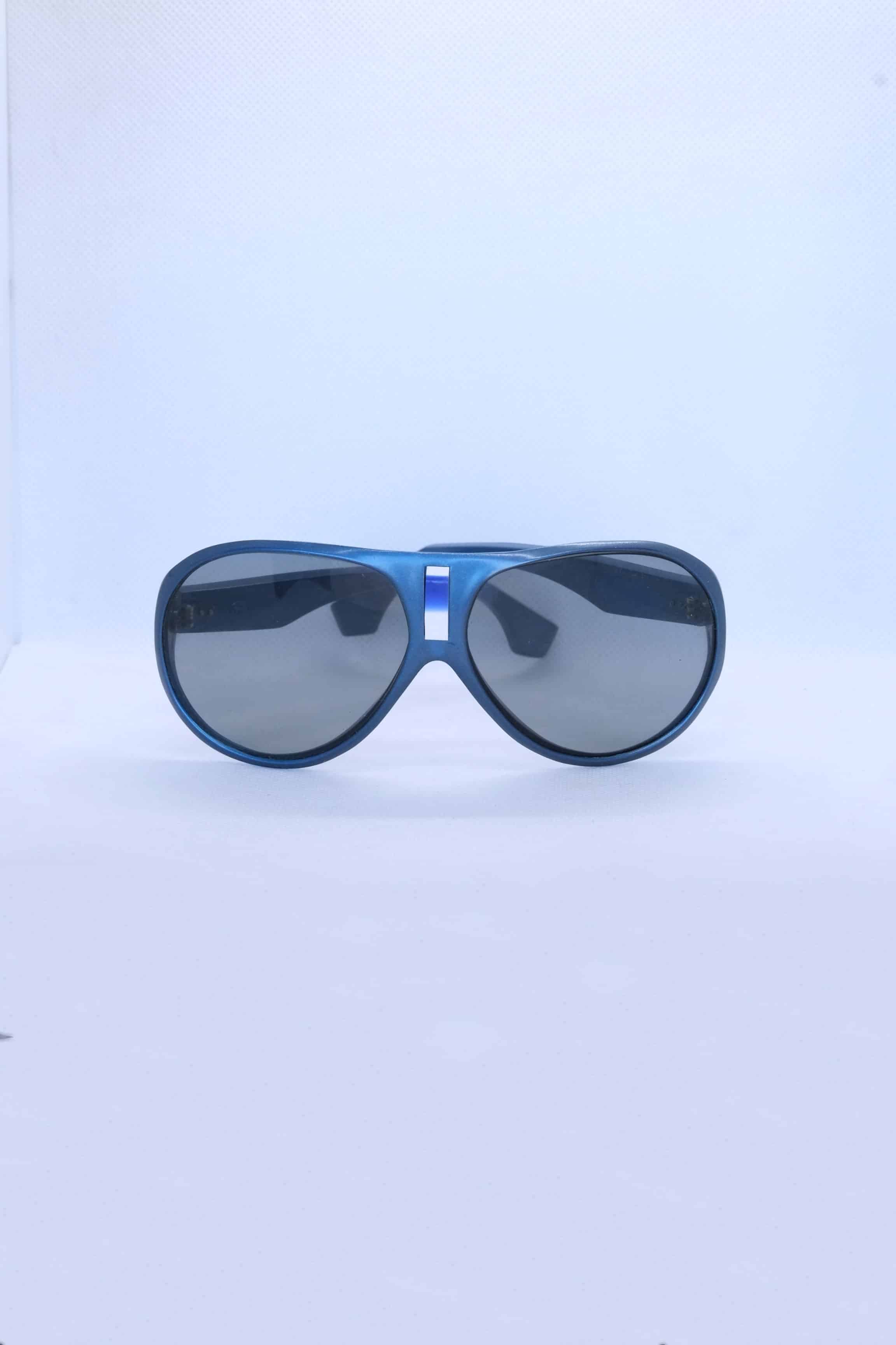 Front view of vintage 1970s SKILOOK metallic dark blue shield-style alpine sunglasses featuring a silver nose bridge insert and gray lenses against a white backdrop.