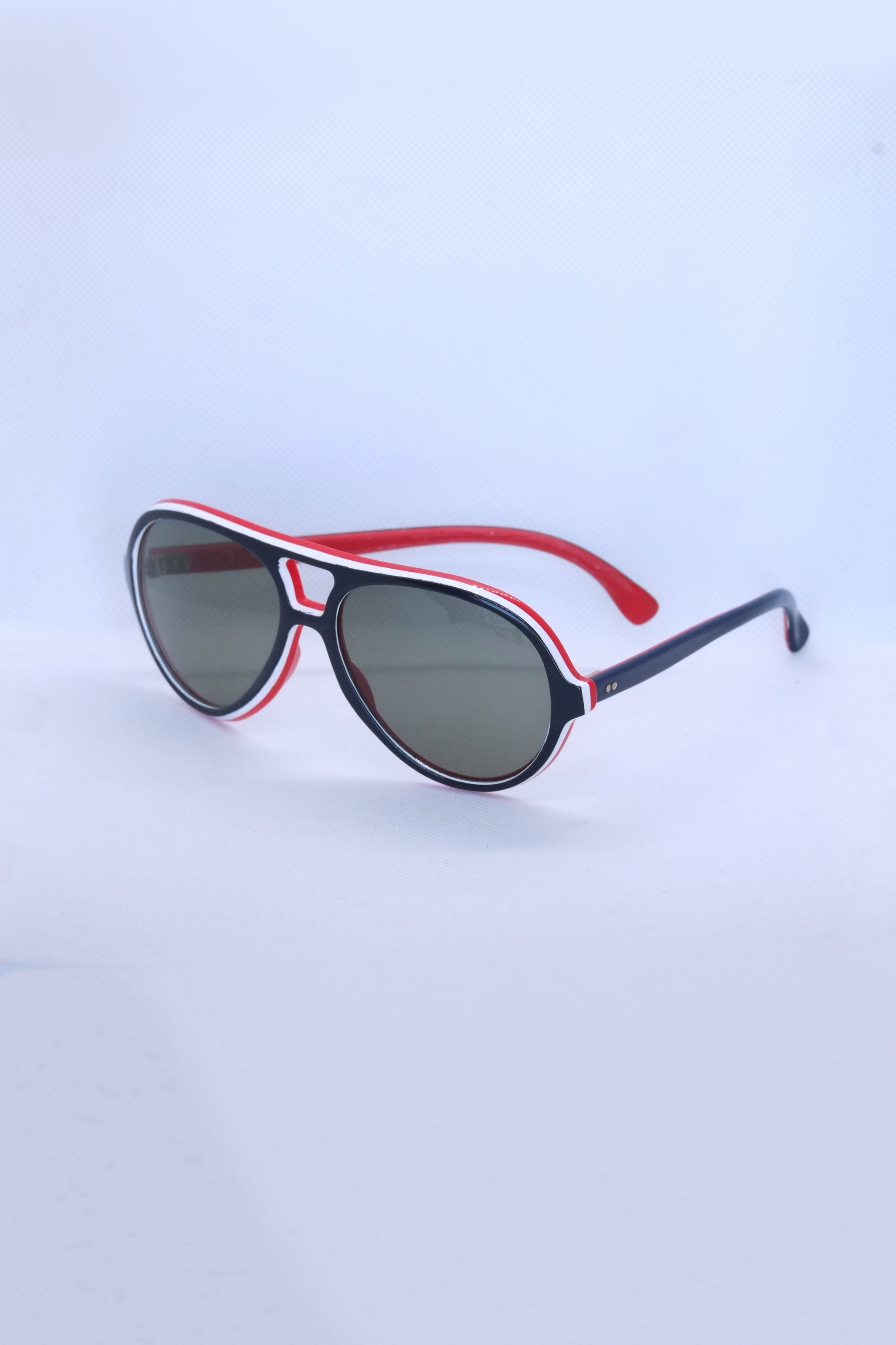 Angled view of vintage 1970s SKILOOK tricolor drop aviator sunglasses with a navy blue frame, red inner rim, white pinstripe accents, and dark grey lenses.