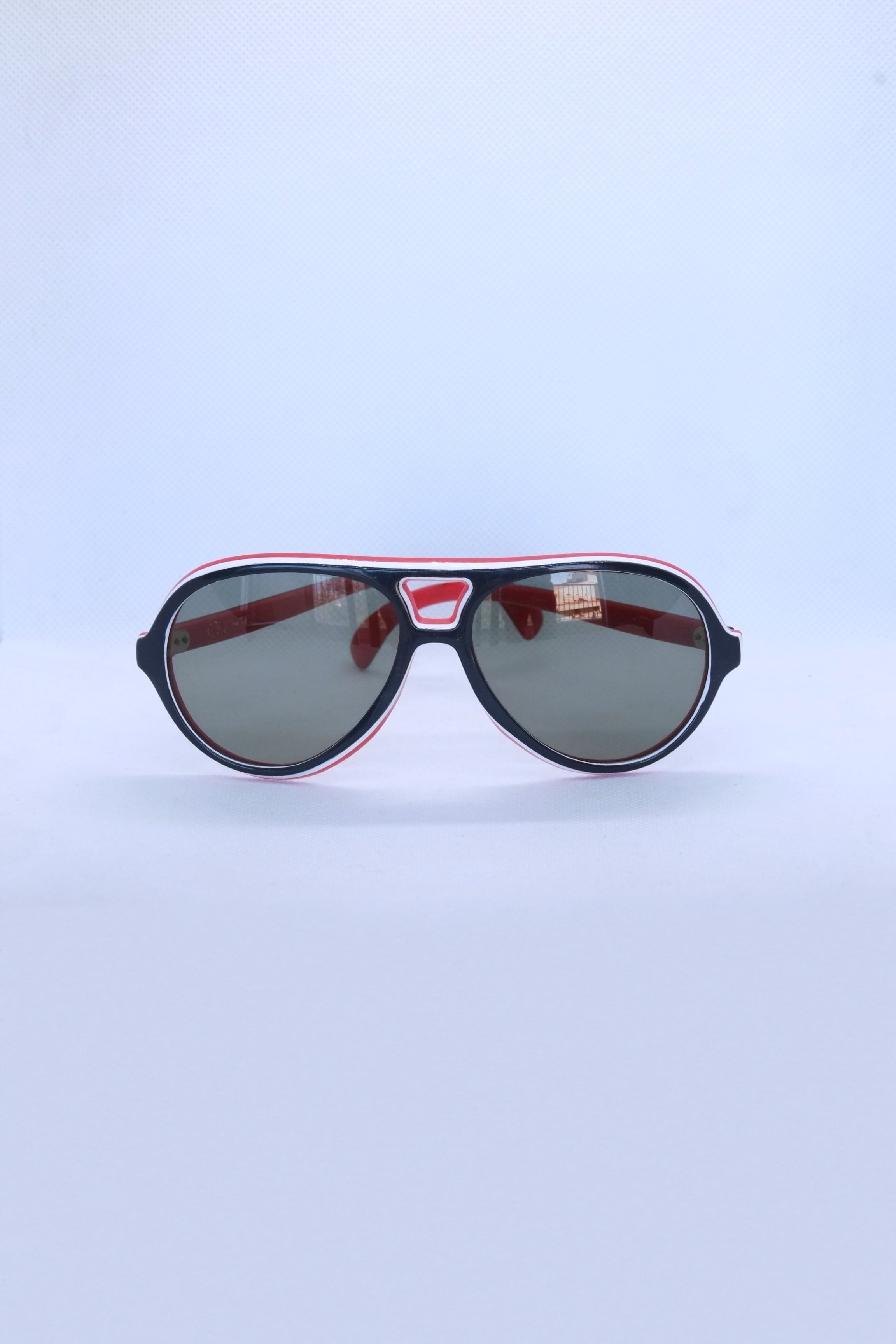 Front view of vintage 1970s SKILOOK tricolor drop aviator sunglasses with a navy blue frame, red inner rim, white pinstripe accents, and dark grey lenses.