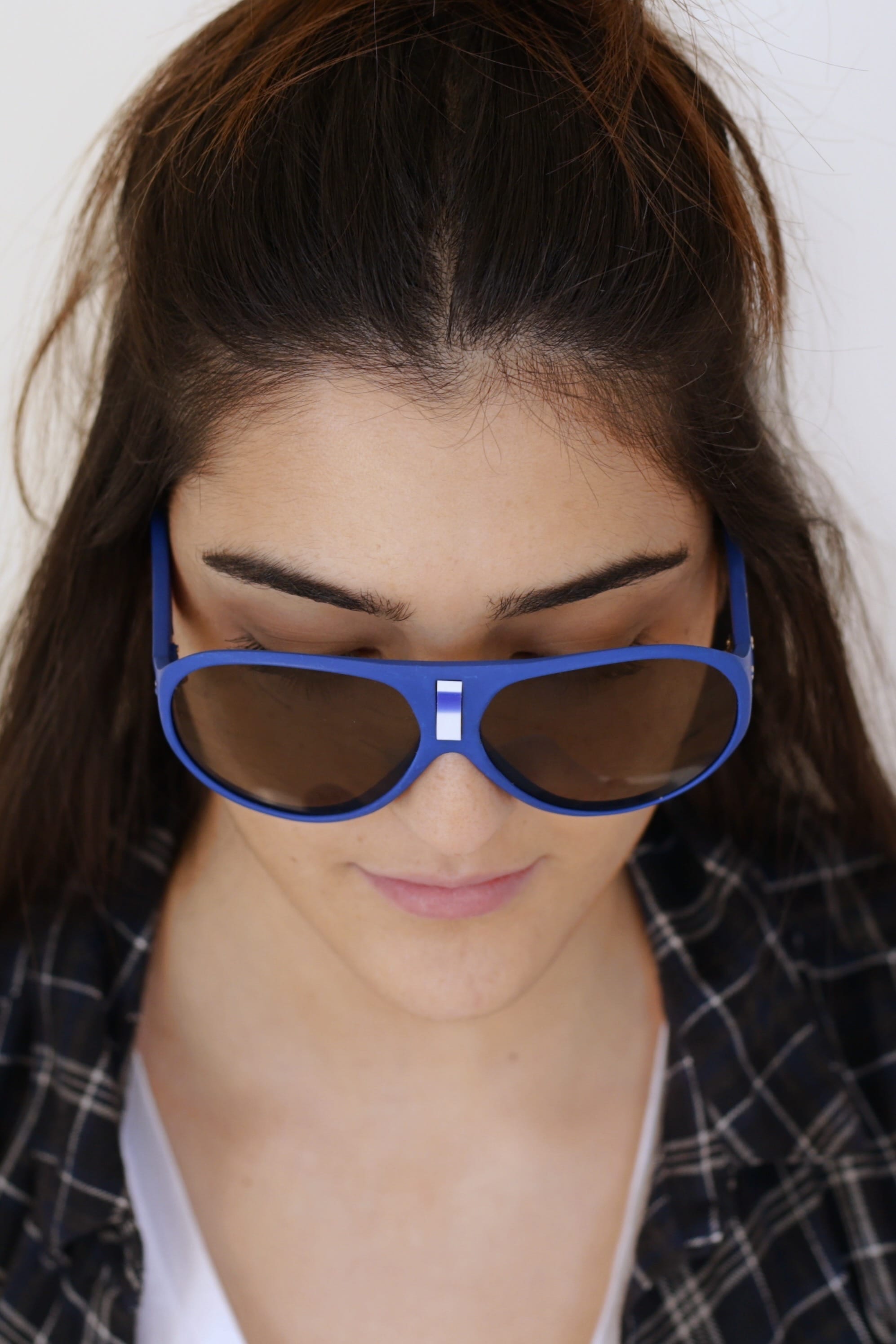 Close-up product model view from above showing a person wearing vintage 1970s SKILOOK matte cobalt blue shield-style alpine sunglasses with a silver nose bridge insert and dark tinted lenses.