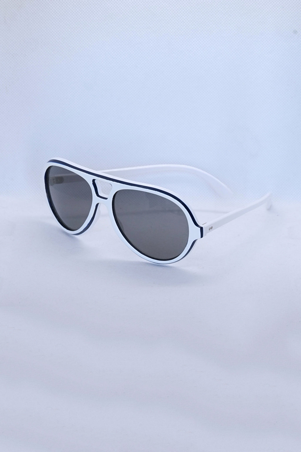Angled view of vintage 1970s SKILOOK tricolor drop aviator sunglasses featuring a crisp white acetate frame with navy blue outer trim and dark gray lenses.