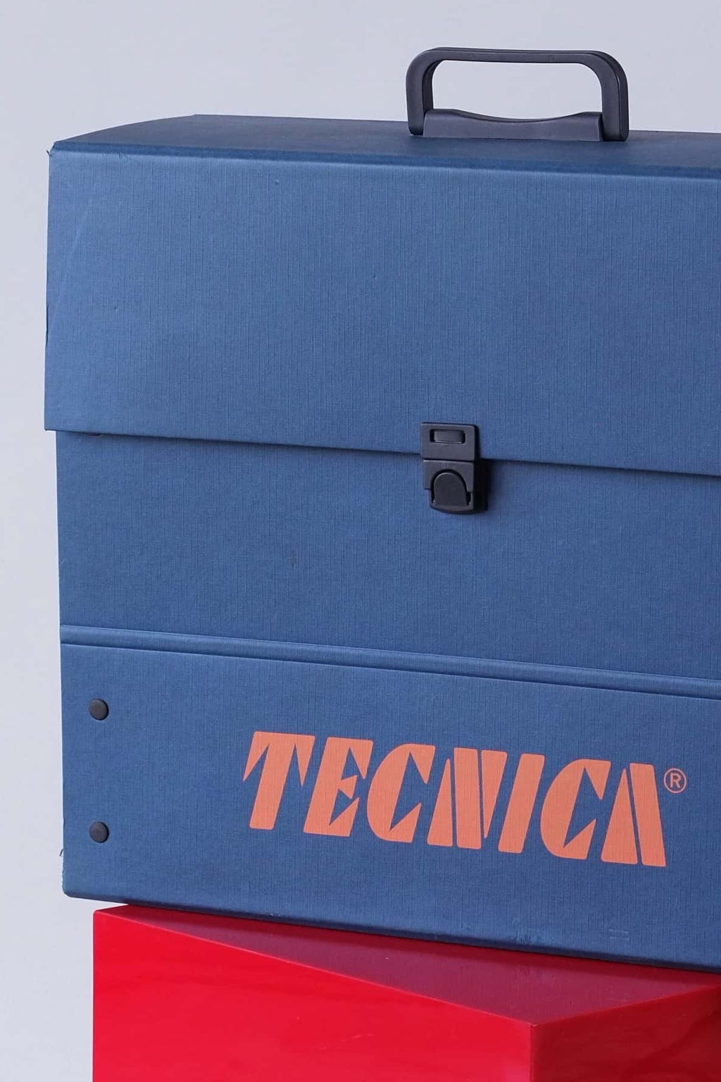 Detail shot showing corner of the Tecnica case with rivets and part of the orange logo.