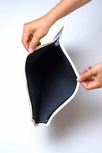 Hands pulling open a vintage white vinyl Tretorn tennis racket cover, showcasing the clean, dark blue fabric interior lining and black zipper track.