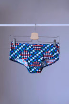swim briefs in a geometric pattern of blue,  green, white, red on a hanger