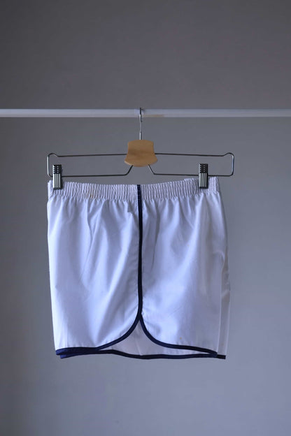 TROPIC Vintage Men's White Shorts on a hanger, viewed from the left side, highlighting the side trim detail.