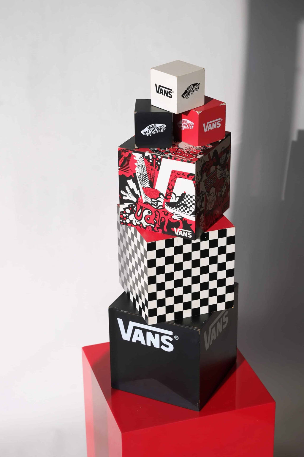 Vintage 2000s VANS dealer display cube set with nesting boxes, stacked in full view on a red pedestal, showing graffiti art, checkerboard, and branding.