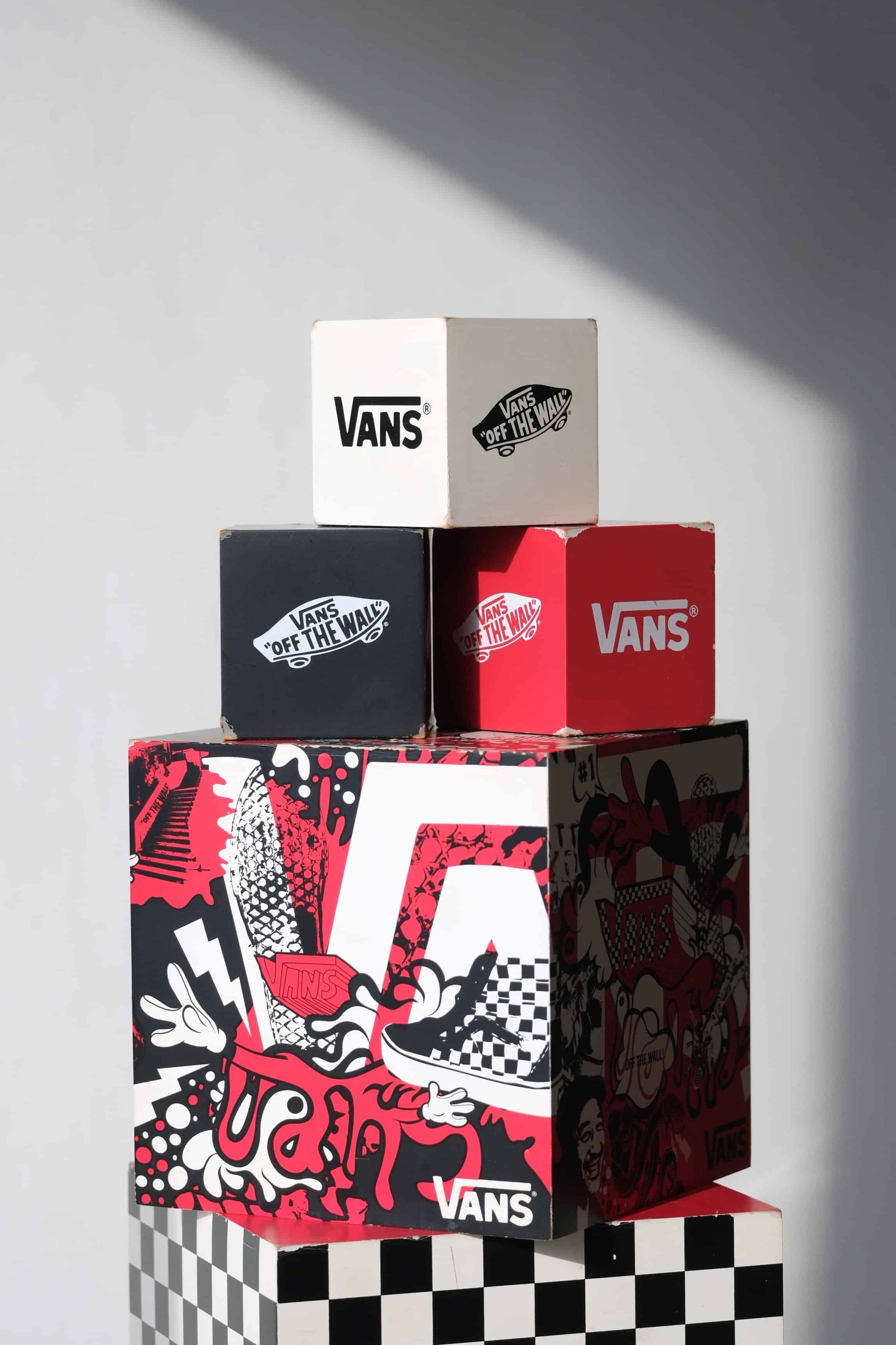 Detailed view of top three VANS nesting display cubes showing light scuffs, logos, and vintage wear on corners.