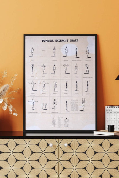 Framed 1970s dumbbell workout chart with orange-yellow wall background, styled with books and dried florals.