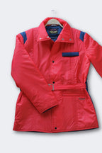 Men's red vintage 80s puffer ski jacket with a belted waist, blue shoulder and pocket details, a stand-up collar, and a zipper/snap button closure.