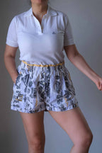 Model wearing a white polo and vintage printed volkl tennis shorts