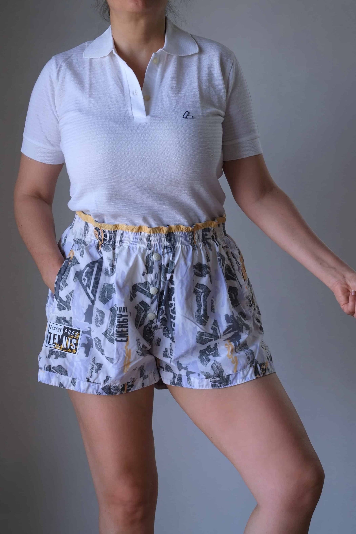 Model wearing a white polo and vintage printed volkl tennis shorts