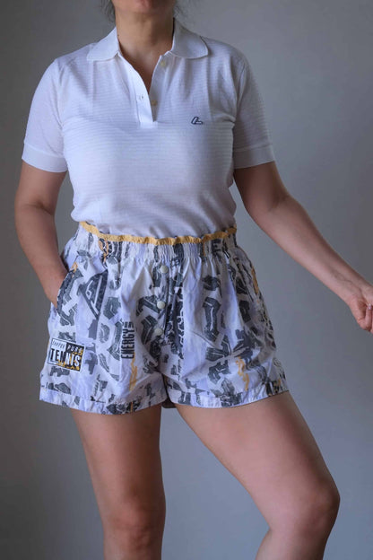 Model wearing a white polo and vintage printed volkl tennis shorts