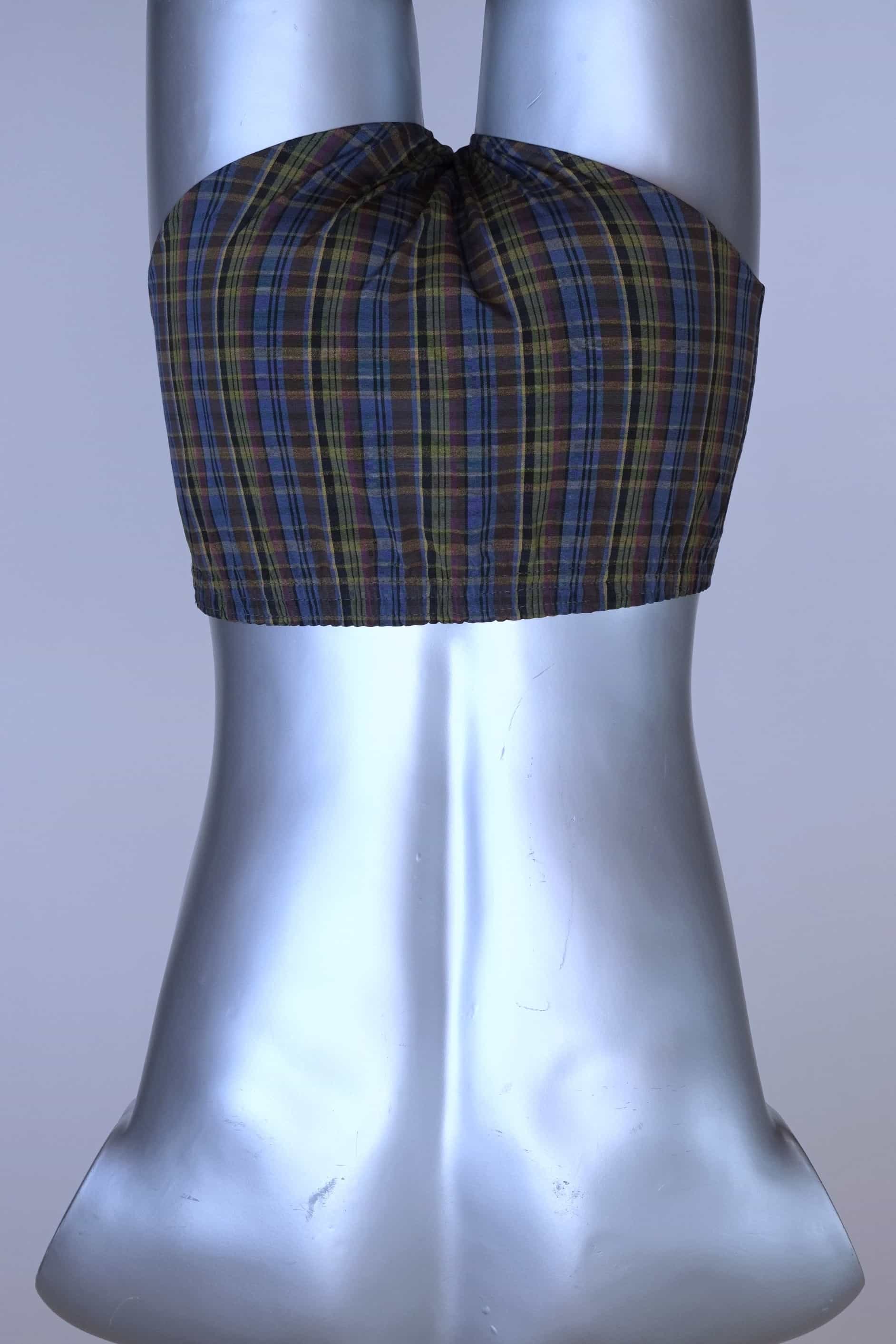 Back view of a vintage late 1950s to early 1960s men's swim brief on a silver mannequin. The brief features a plaid pattern in dark brown, blue, and yellow tones, with a small front flap pocket.