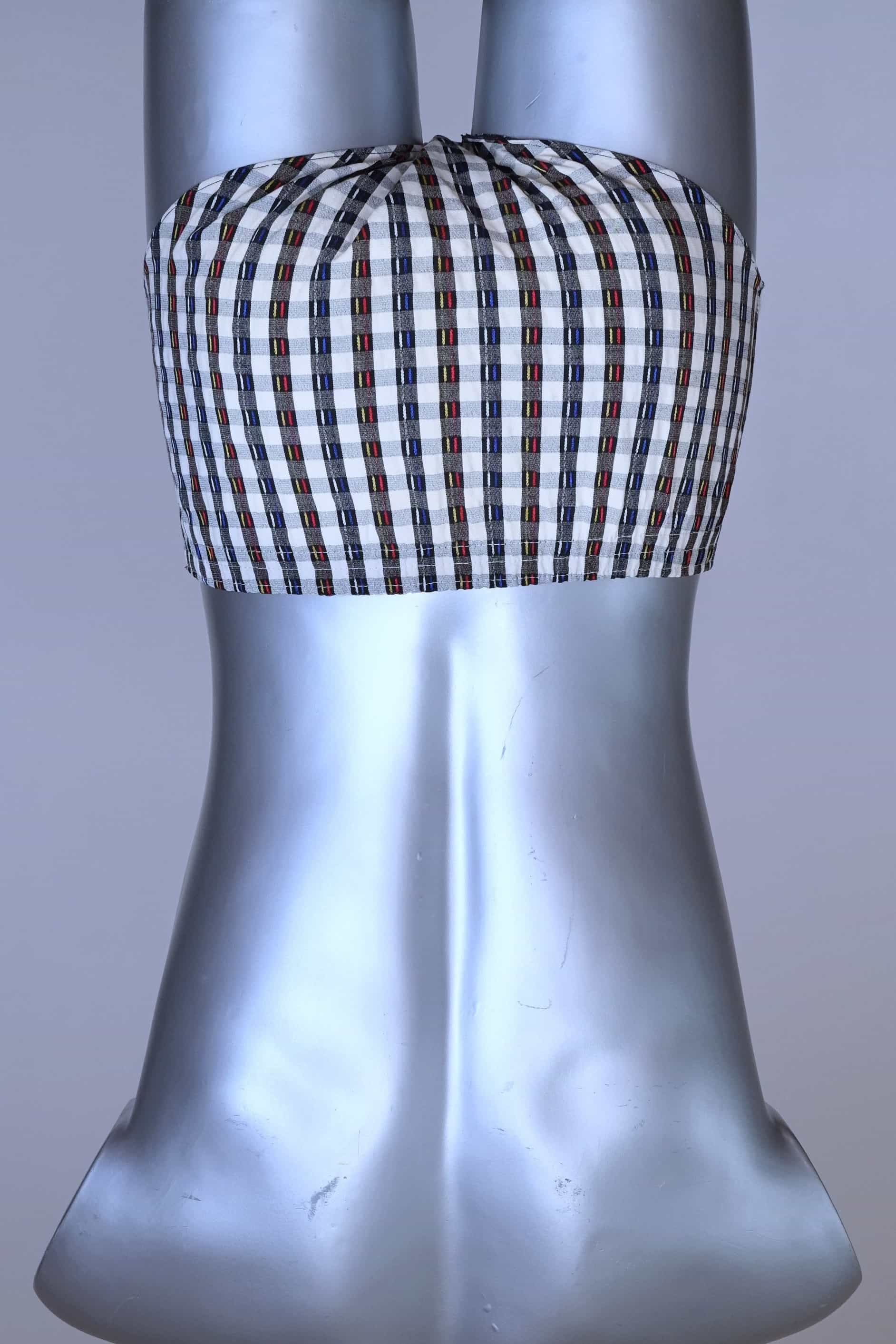 Back view of a vintage late 1950s to early 1960s men's swim brief on a silver mannequin. The brief features a plaid pattern in white, blue, and red, with a small front flap pocket.