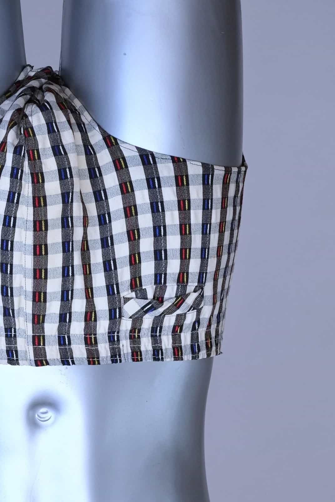 Close view of a vintage late 1950s to early 1960s men's swim brief on a silver mannequin. The brief features a plaid pattern in white, blue, and red, with a small front flap pocket.
