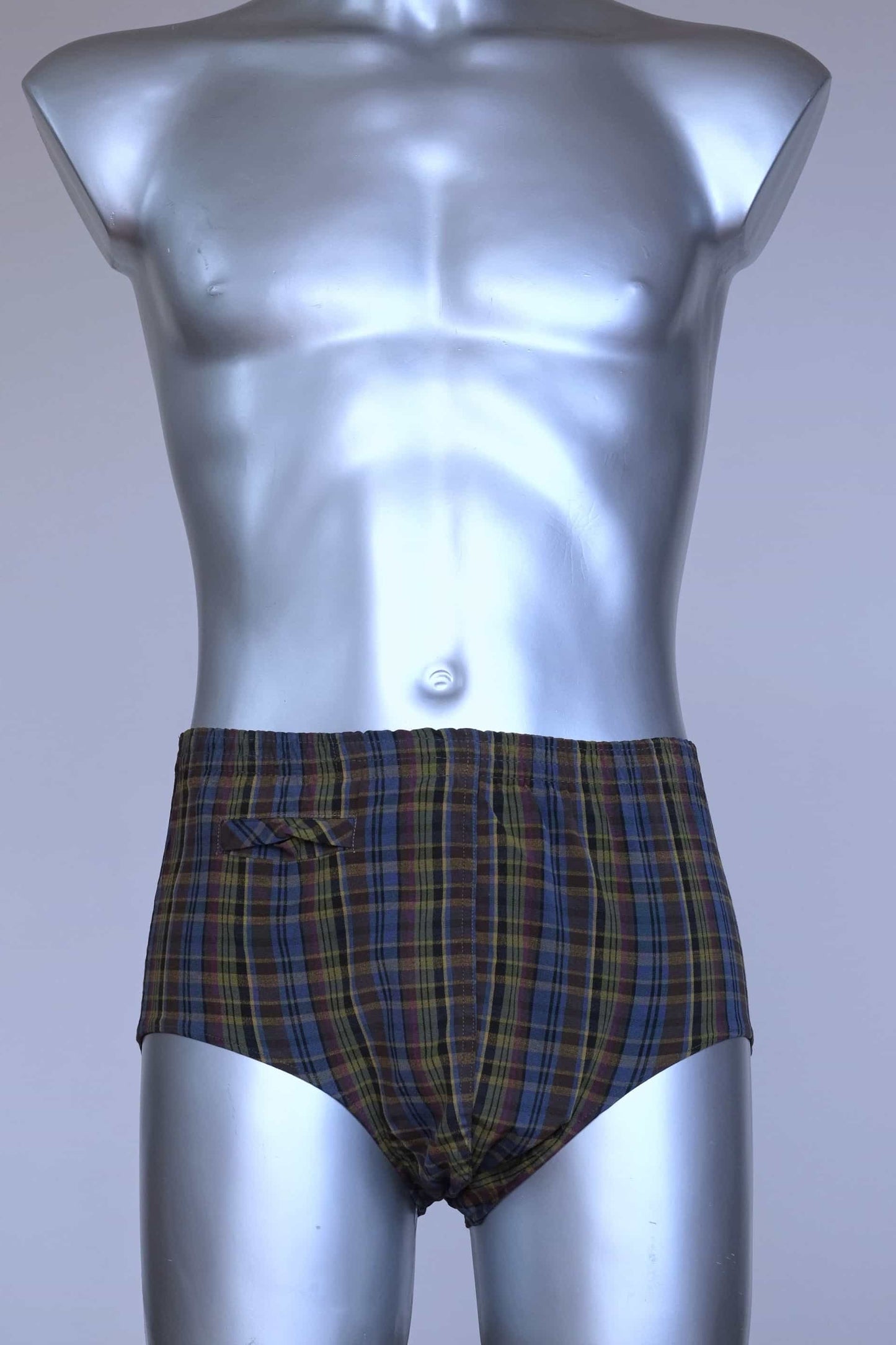 Front view of a vintage late 1950s to early 1960s men's swim brief on a silver mannequin. The brief features a plaid pattern in dark brown, blue, and yellow tones, with a small front flap pocket.