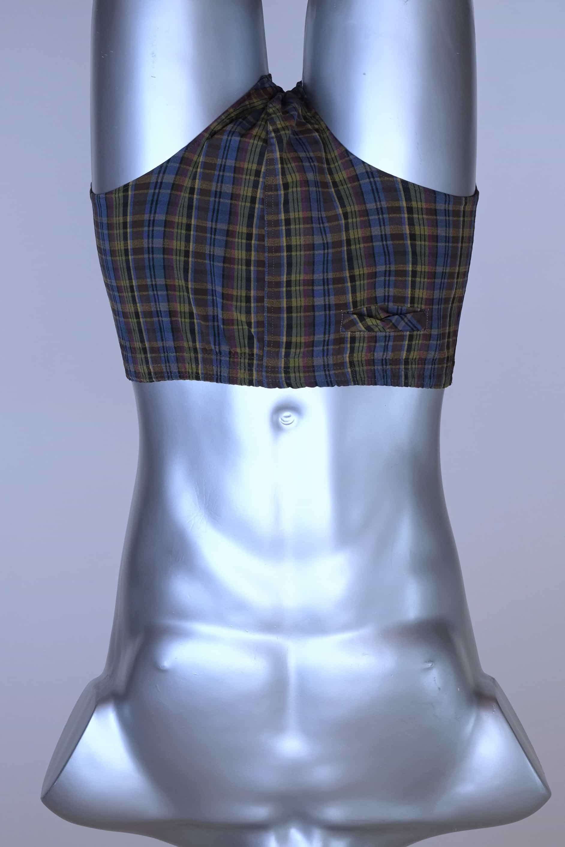 Front view of a vintage late 1950s to early 1960s men's swim brief on a silver mannequin. The brief features a plaid pattern in dark brown, blue, and yellow tones, with a small front flap pocket.