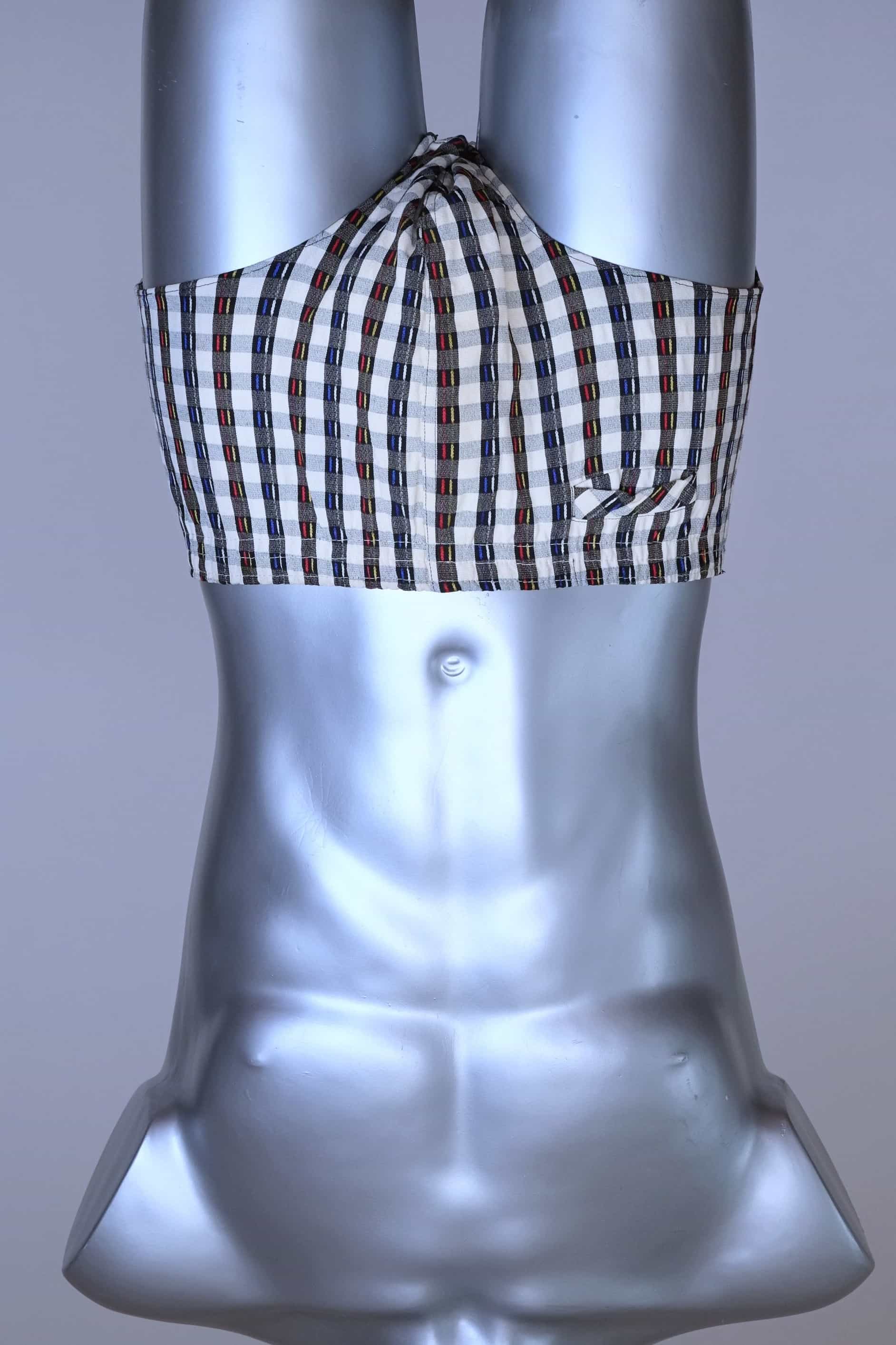 Front view of a vintage late 1950s to early 1960s men's swim brief on a silver mannequin. The brief features a plaid pattern in white, blue, and red, with a small front flap pocket.