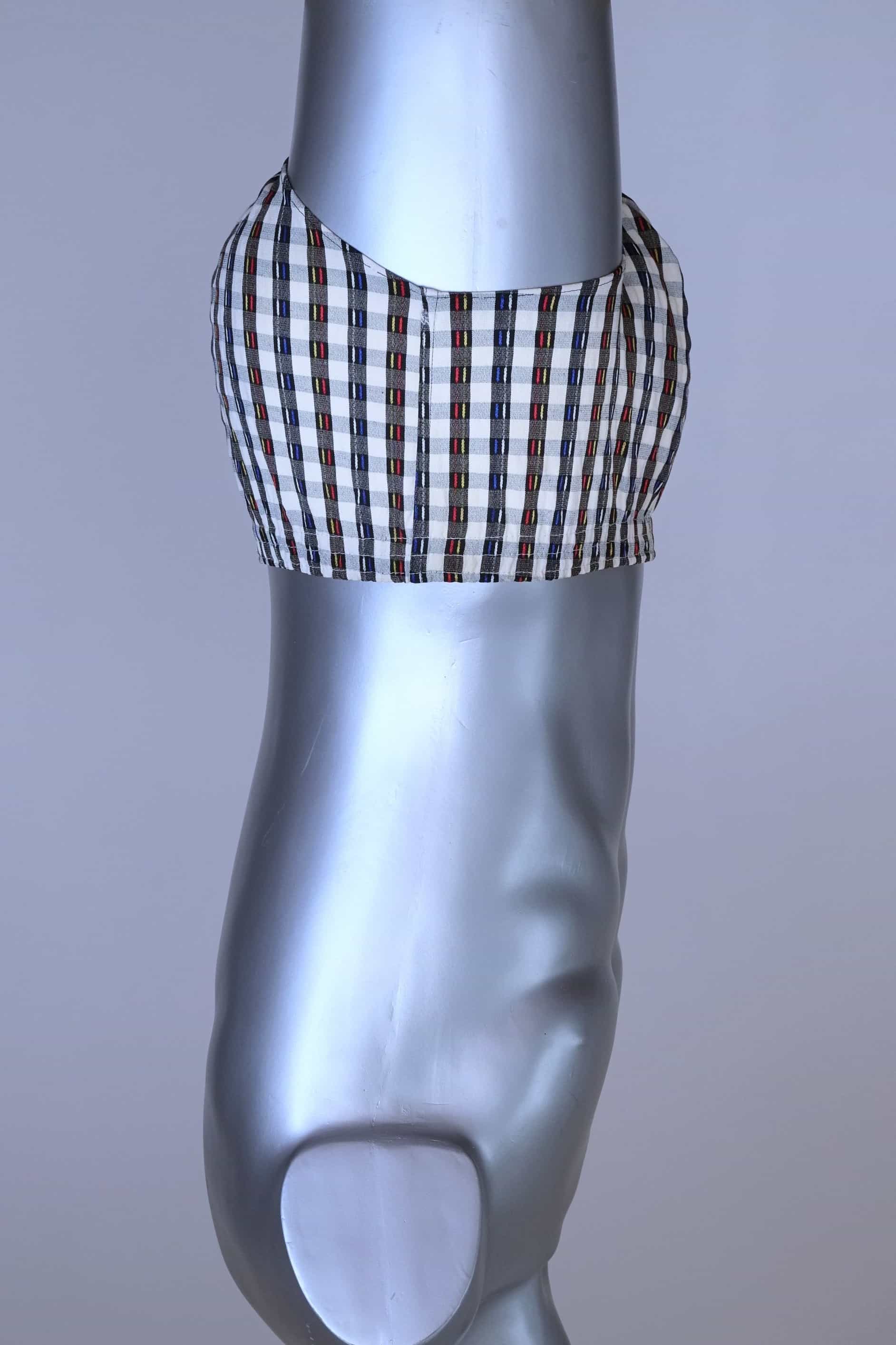 Side view of a vintage late 1950s to early 1960s men's swim brief on a silver mannequin. The brief features a plaid pattern in white, blue, and red, with a small front flap pocket.