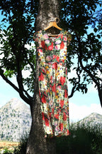 Vintage 90s floral maxi dress hanging on a tree branch outdoors with mountain landscape background