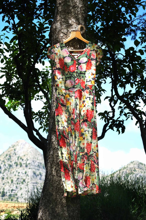 Vintage 90s floral maxi dress hanging on a tree branch outdoors with mountain landscape background