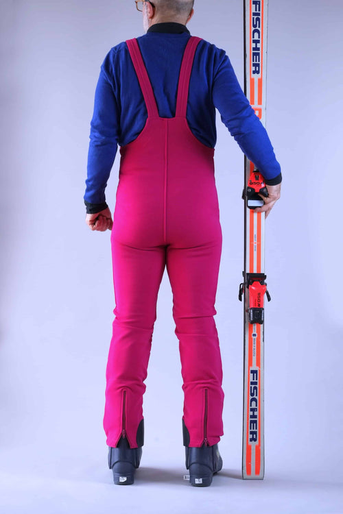 Back view of a person wearing a raspberry pink vintage 90s ski bibs with a high-waisted fit, slalom-style knee pads, and zippered leg openings.