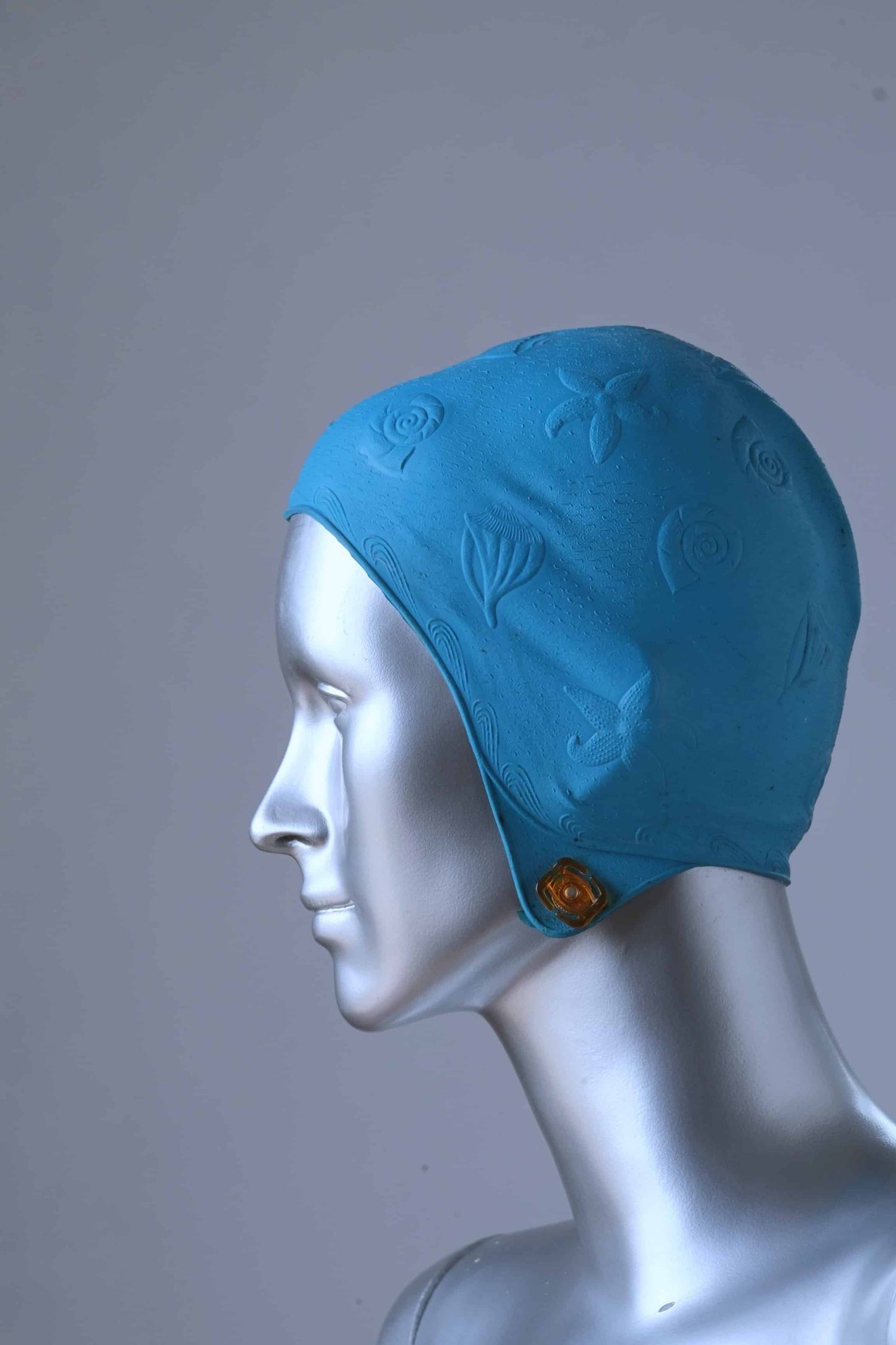 A mannequin wearing a vintage blue swim cap in a pattern showing multiple seashells. 