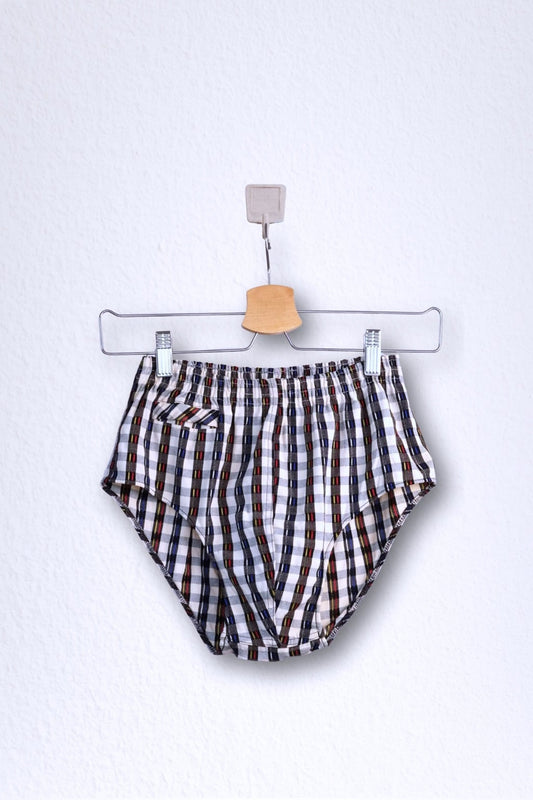 Front view of a vintage late 1950s to early 1960s men's swim brief on a hanger. The brief features a plaid pattern in white, blue, and red, with a small front flap pocket.