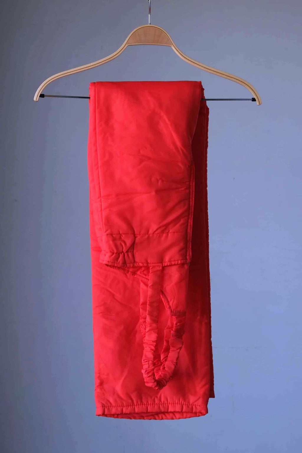 Vintage 70s Warmia ski bib photographed folded over a wooden hanger against a grey background.