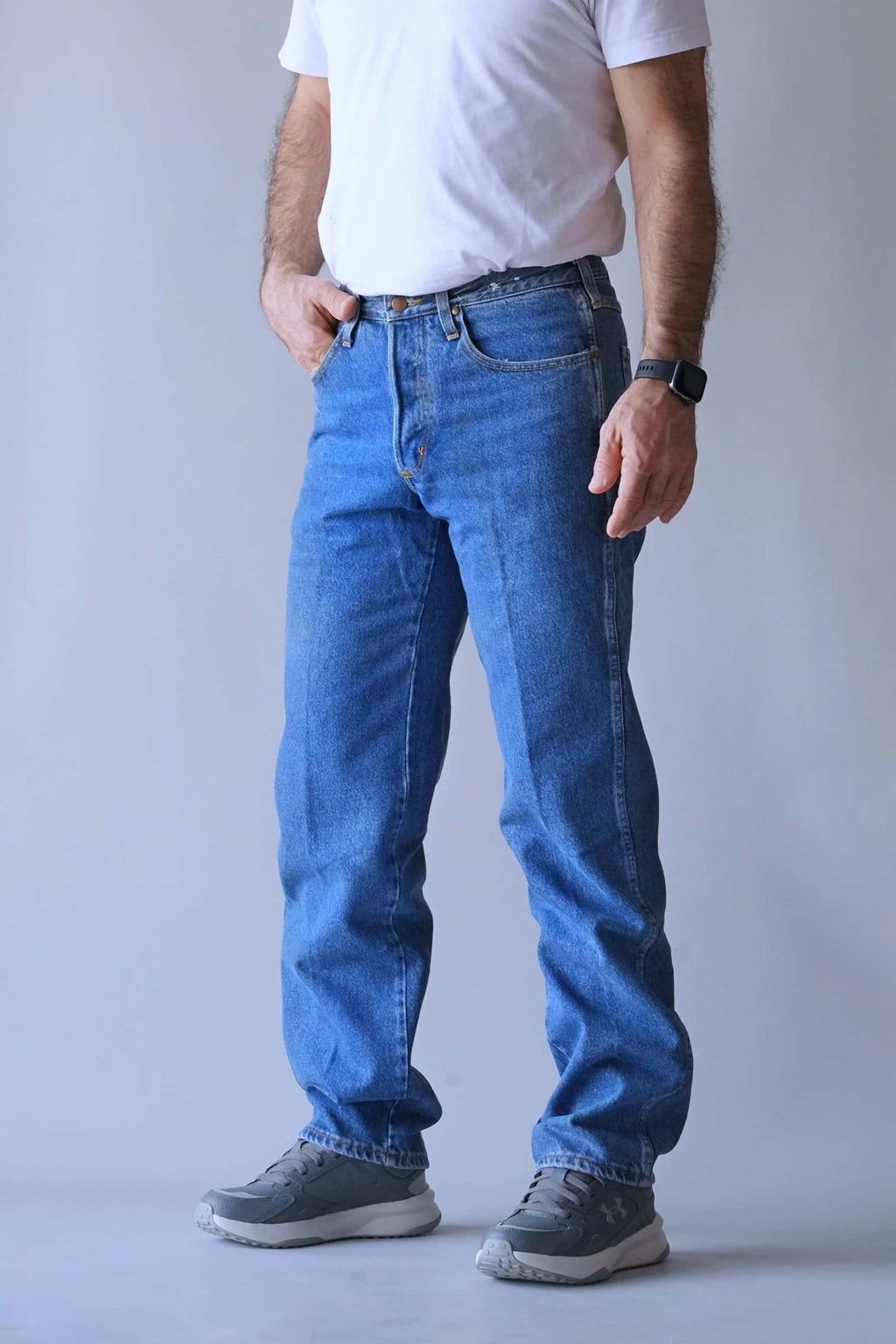 Side-angle view of a person wearing Wrangler mid-wash straight-leg jeans.