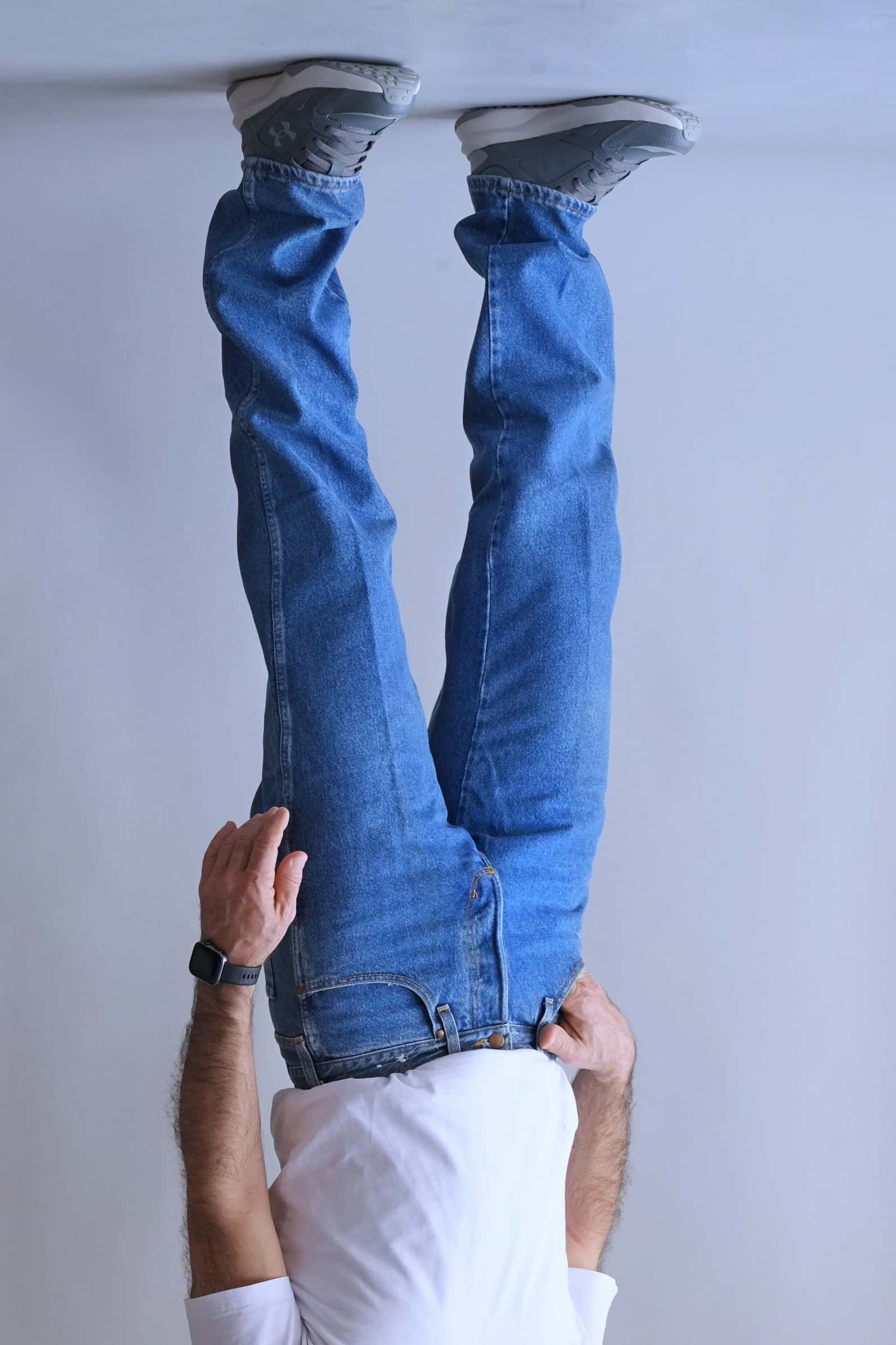Side-angle view of a person wearing Wrangler mid-wash straight-leg jeans.